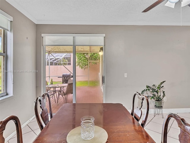 tiled dining room with ceiling fan, crown molding, and a textured ceiling