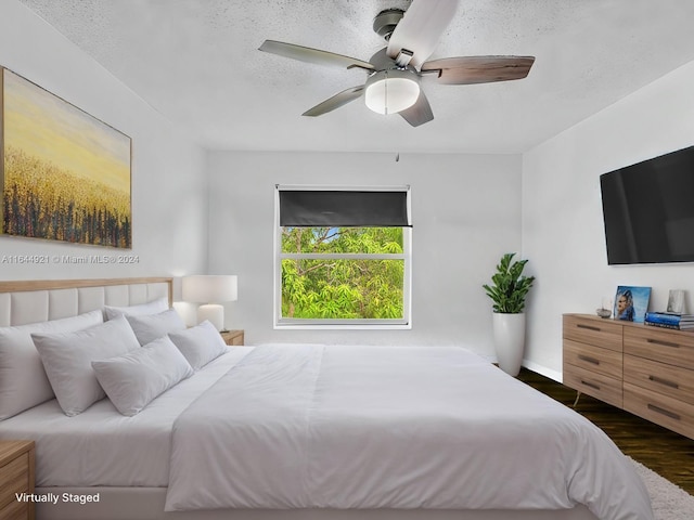 bedroom with a textured ceiling, ceiling fan, and dark wood-type flooring