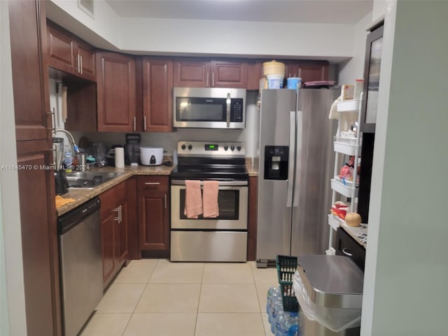 kitchen featuring visible vents, a sink, stainless steel appliances, light tile patterned floors, and light stone countertops