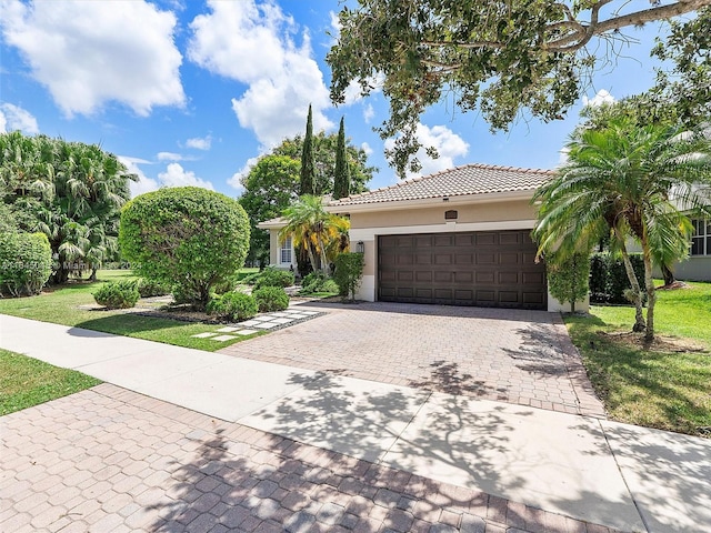 view of front of property with a front yard, stucco siding, a garage, a tiled roof, and decorative driveway