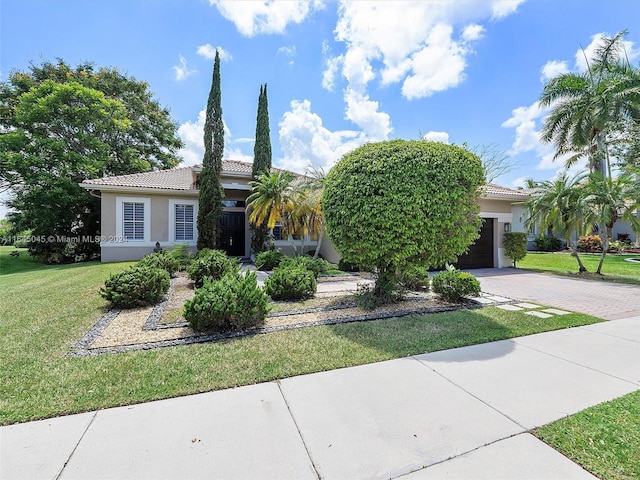 view of front of house featuring stucco siding, a tile roof, decorative driveway, and a front yard