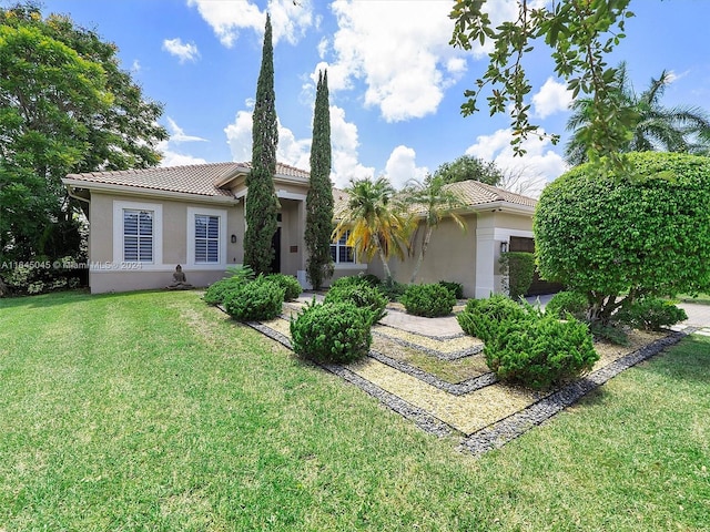 view of front of home featuring stucco siding, a front yard, and a tile roof