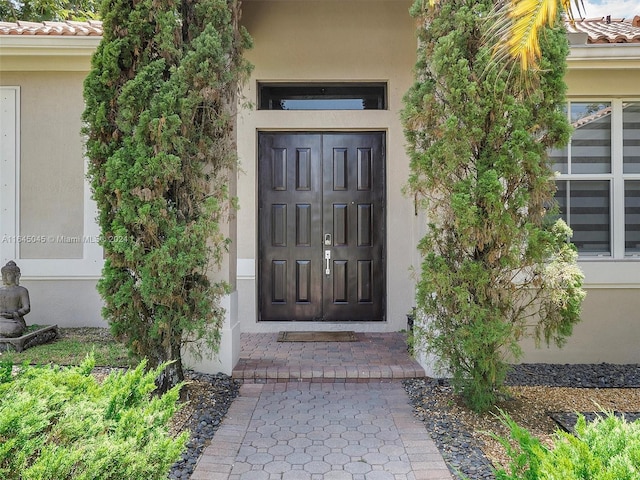 doorway to property with a tile roof and stucco siding