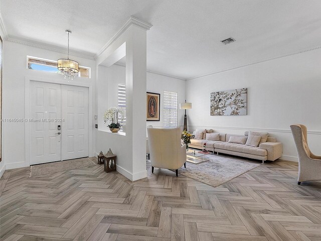 entryway featuring light parquet flooring, a notable chandelier, a textured ceiling, and ornamental molding