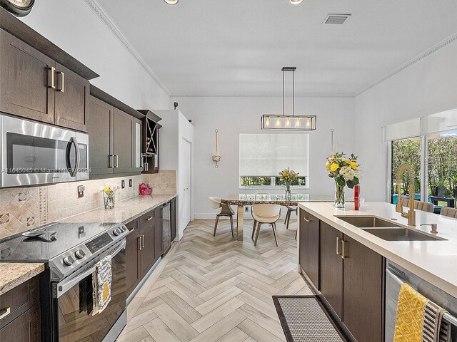 kitchen with appliances with stainless steel finishes, backsplash, sink, pendant lighting, and light parquet flooring