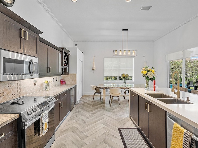 kitchen with a sink, ornamental molding, light countertops, stainless steel appliances, and tasteful backsplash