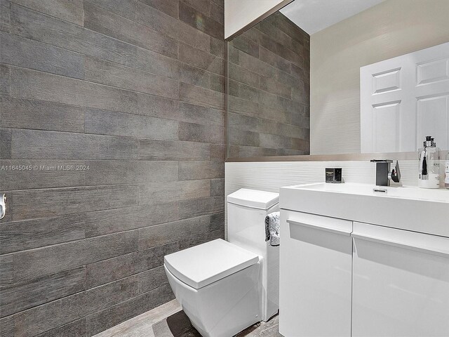 bathroom with tile walls, vanity, and toilet