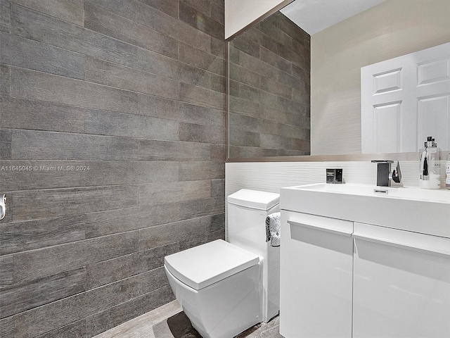 half bathroom featuring toilet, tile walls, and vanity