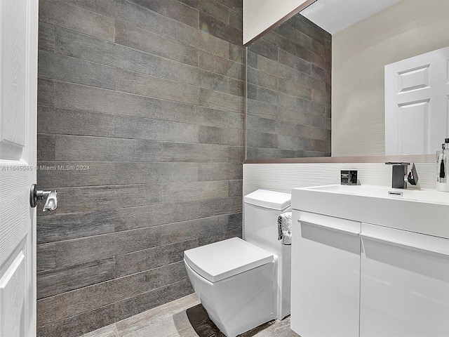 bathroom featuring vanity, tile walls, and toilet