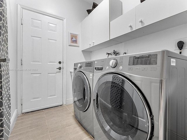 clothes washing area featuring cabinet space, washing machine and dryer, and light wood-style flooring