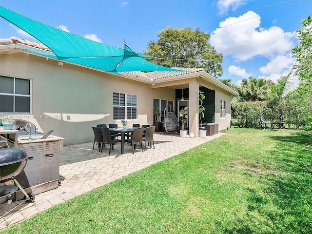 rear view of house featuring a yard, a patio, a tile roof, and stucco siding