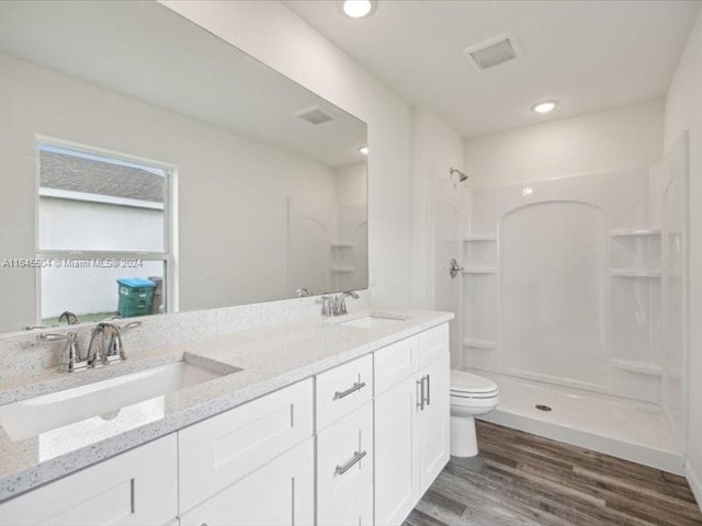 bathroom with vanity, toilet, hardwood / wood-style flooring, and a shower