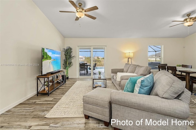 living room featuring a healthy amount of sunlight, ceiling fan, hardwood / wood-style floors, and vaulted ceiling