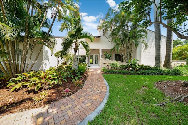 view of front of property featuring french doors, a front lawn, and stucco siding