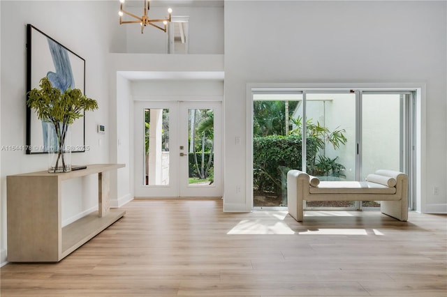 doorway featuring wood finished floors, a towering ceiling, baseboards, french doors, and an inviting chandelier