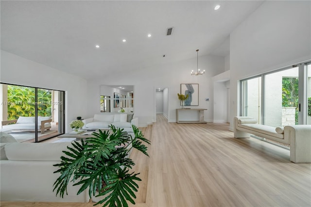 unfurnished living room featuring high vaulted ceiling, visible vents, baseboards, light wood-style floors, and an inviting chandelier