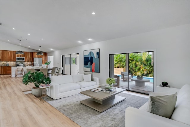 living area featuring vaulted ceiling, light wood finished floors, and recessed lighting