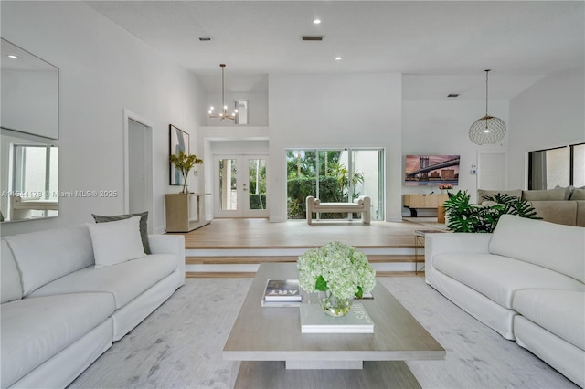 living area featuring visible vents, french doors, light wood-style flooring, and a towering ceiling