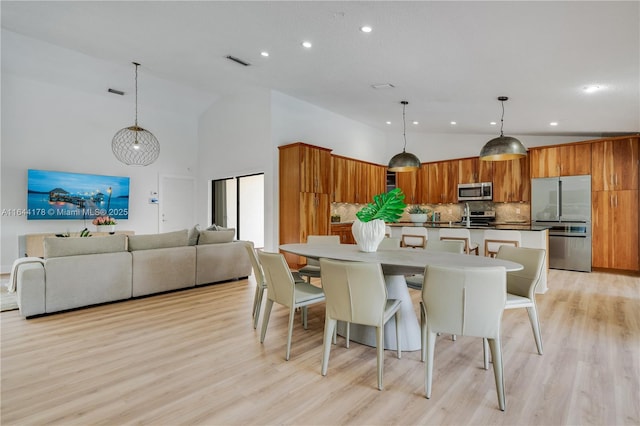 kitchen with appliances with stainless steel finishes, brown cabinets, high vaulted ceiling, and decorative backsplash