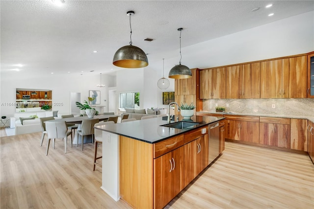 kitchen featuring brown cabinetry, open floor plan, a sink, and light wood finished floors