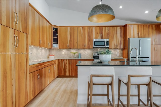 kitchen with lofted ceiling, stainless steel microwave, a breakfast bar area, and freestanding refrigerator