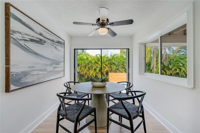 dining area featuring a textured ceiling, a ceiling fan, light wood-style flooring, and baseboards