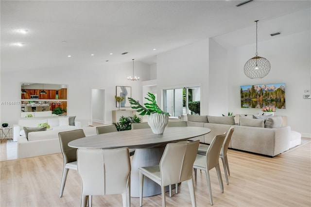 dining area with high vaulted ceiling, light wood-style flooring, recessed lighting, a notable chandelier, and visible vents