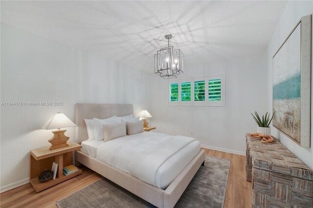 bedroom featuring an inviting chandelier, wood finished floors, and baseboards