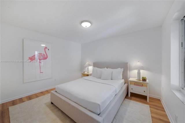 bedroom featuring light wood finished floors and baseboards