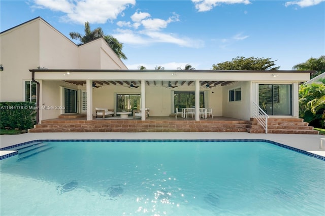 back of property featuring a patio area, an outdoor pool, a ceiling fan, and stucco siding