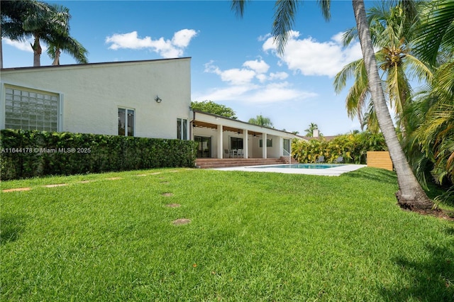 back of property featuring a patio, an outdoor pool, a lawn, and stucco siding