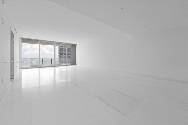 spare room with floor to ceiling windows and light tile patterned floors