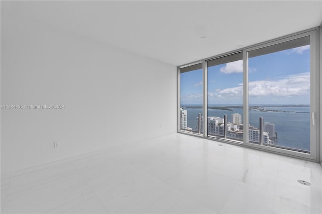 unfurnished room featuring a water view and floor to ceiling windows