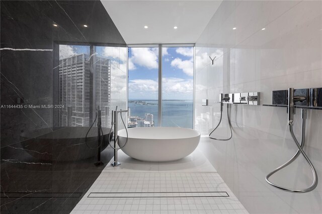 bathroom with a water view, tile patterned flooring, a wall of windows, tile walls, and shower with separate bathtub