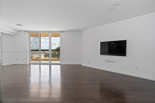 unfurnished living room with a wall of windows and dark hardwood / wood-style floors