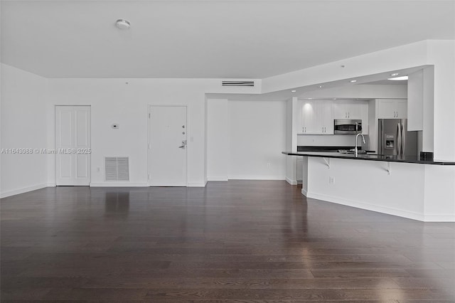 unfurnished living room featuring dark wood-type flooring and sink