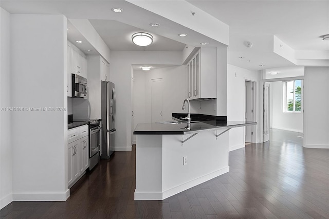 kitchen featuring a kitchen bar, sink, kitchen peninsula, stainless steel appliances, and white cabinets