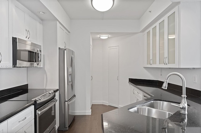 kitchen with sink, appliances with stainless steel finishes, dark stone countertops, dark hardwood / wood-style floors, and white cabinets