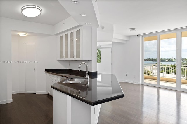 kitchen with sink, a water view, expansive windows, white cabinets, and kitchen peninsula