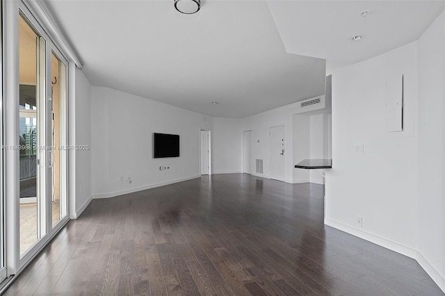 unfurnished living room with dark wood-type flooring and a healthy amount of sunlight