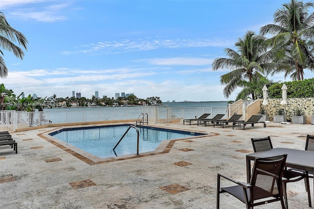 view of swimming pool featuring a water view and a patio