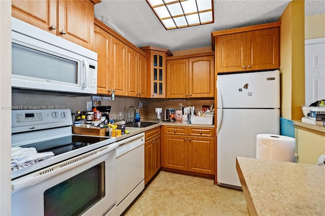 kitchen with sink, a textured ceiling, light tile patterned flooring, and white appliances