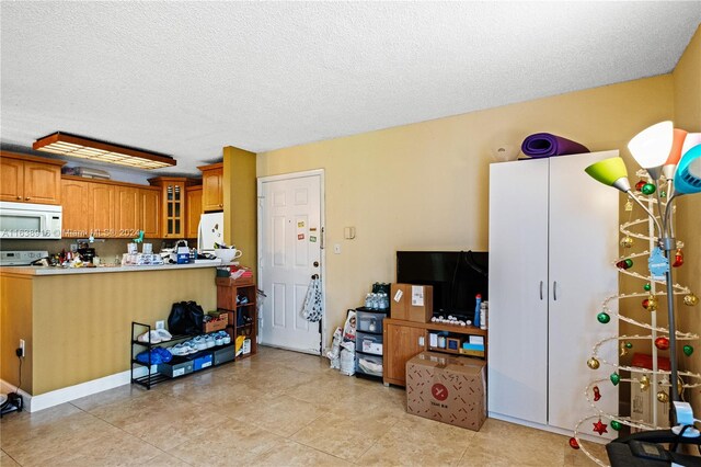 kitchen featuring light tile patterned flooring, a textured ceiling, and refrigerator