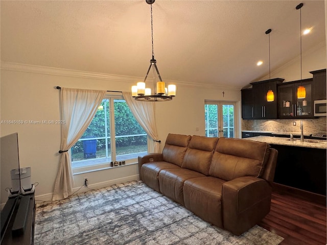 living room featuring sink, french doors, a chandelier, lofted ceiling, and hardwood / wood-style flooring