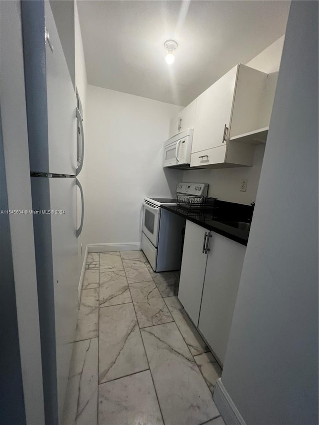 kitchen featuring light tile patterned floors, white appliances, and white cabinets