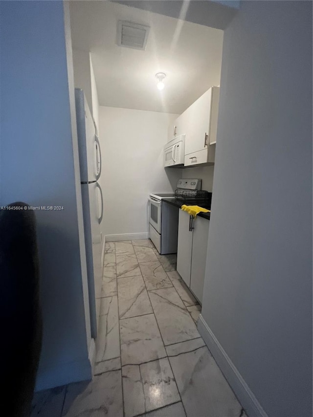 kitchen with white cabinetry, light tile patterned floors, and white appliances