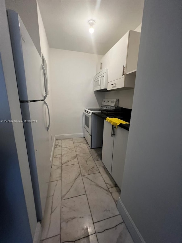 kitchen with white cabinetry, light tile patterned flooring, and white appliances