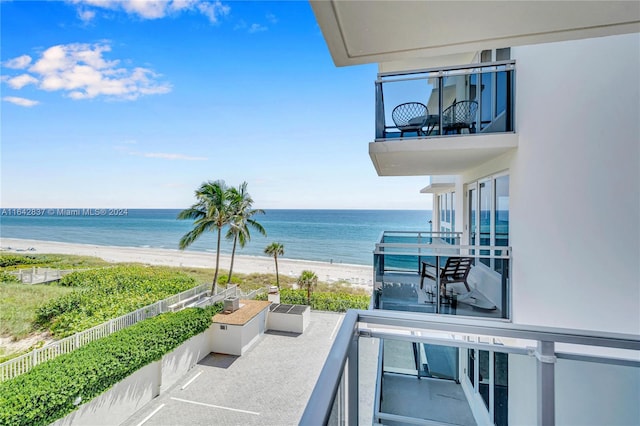 balcony featuring a view of the beach and a water view