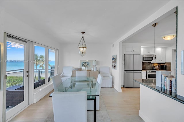 dining area with light hardwood / wood-style floors and a water view