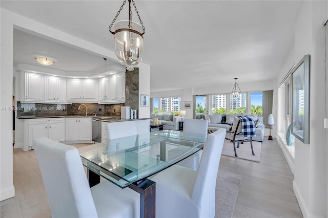 dining area with sink, light hardwood / wood-style flooring, and a notable chandelier